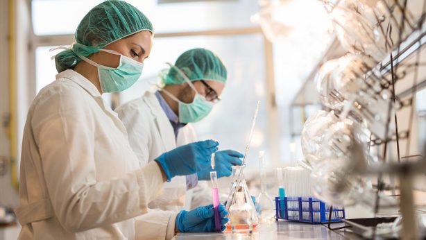 Two scientists in lab coats and masks conducting experiments in a laboratory.
