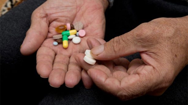 Hands holding various colorful pills and tablets.